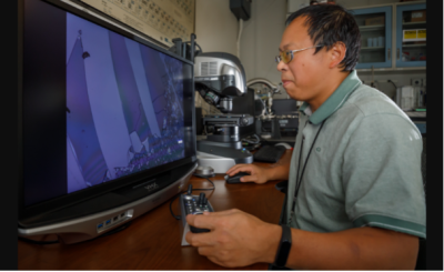 SNL researcher Guangping Xu employs a digital optical microscope to examine the unusually hard coatings his lab has produced