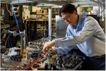 SNL’s Jongmin Lee examines the sensor head of a cold-atom interferometer